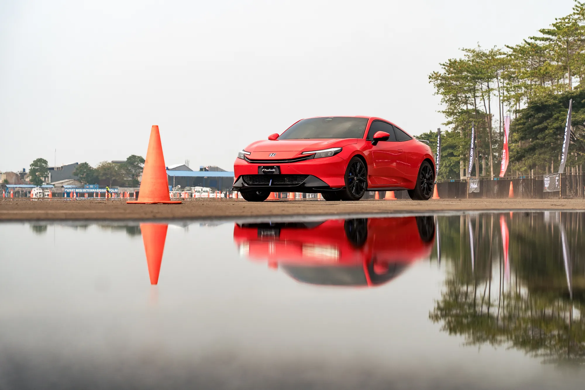 Honda Prelude merah dengan pantulan di permukaan air di area test drive
